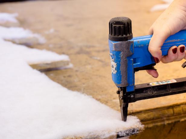 Spray adhesive onto the boardâs surface then roll out batting on top. Press into place, then trim neatly along the edges . To ensure batting stays put, staple once on each corner Repeat on either side of each board.