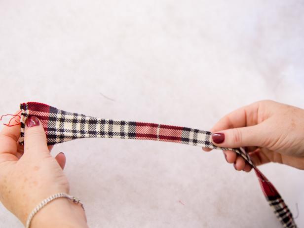 Using the same or a coordinating fabric, cut 2 inch wide strips at a length that will accommodate the perimeter of your trees. Neatly fold fabric over to hide rough edges and iron to get a tailored look Place center of the strip at top of tree board and secure with one nail head. Continue adding nail heads along the edge, starting with corner and filling in so that the trim is pulled tight along the edge working your way down the tree. Repeat on other board.