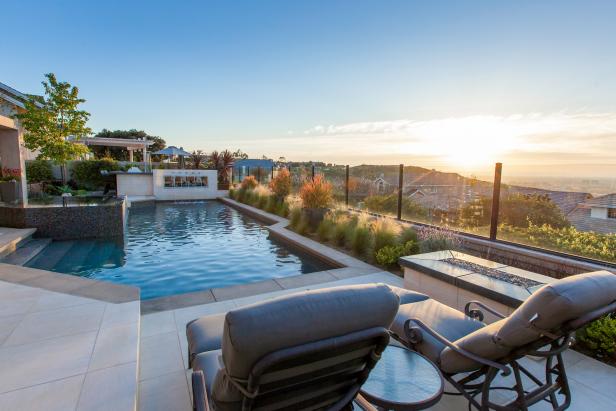 Plant-Bordered Swimming Pool With Neutral Lounge Chairs and Fire Pit Plant-Bordered Swimming Pool With Neutral Lounge Chairs and Fire Pit