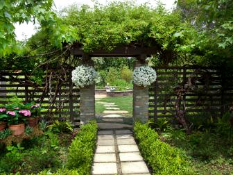 A trellis and archway are canopied by lush greenery