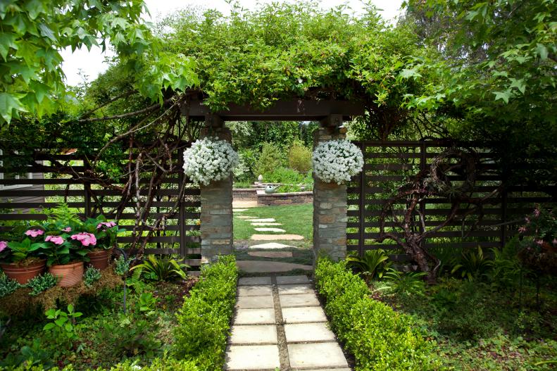 A trellis and archway are canopied by lush greenery