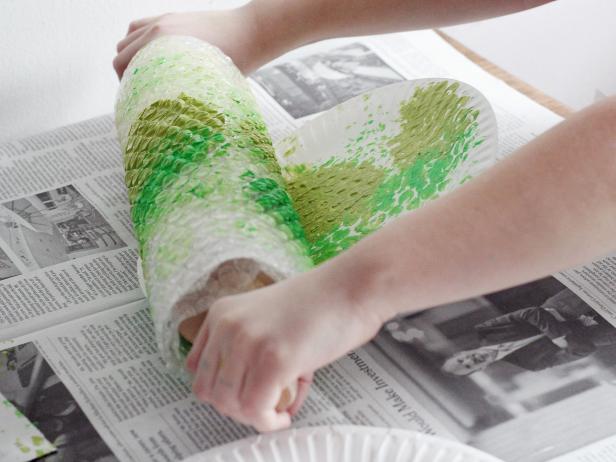 girl rolling bubble wrap in green paint