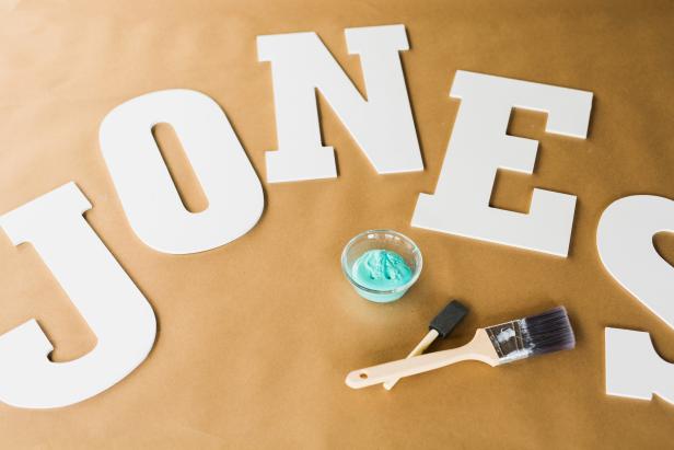 Cover a flat, level work surface with contractor paper. Next, lay the letters and painting supplies out on the work surface.