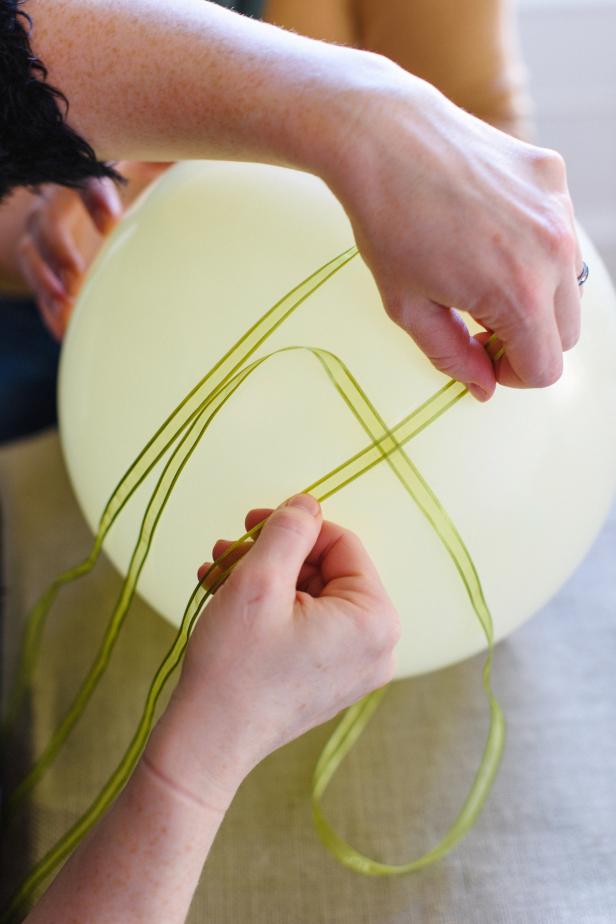 Lay the middle of one ribbon across the tape and press down to secure. Place another piece of tape on top of that ribbon and lay the second ribbon crosswise over the other. Press down to secure.