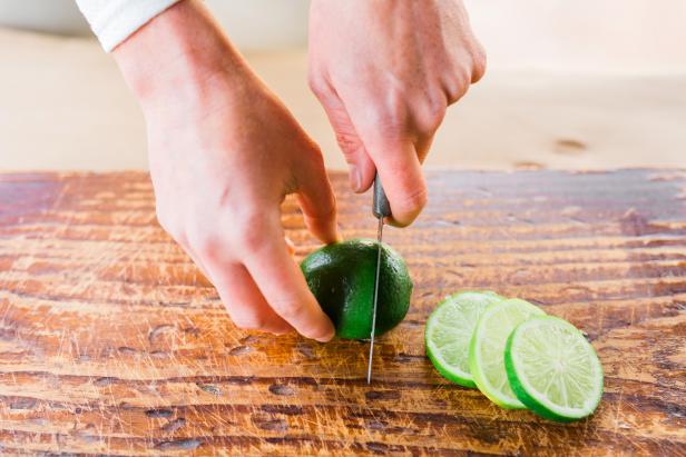 Place the limes, lemons or oranges on a cutting board; then cut them into 1/4" slices using a paring knife.