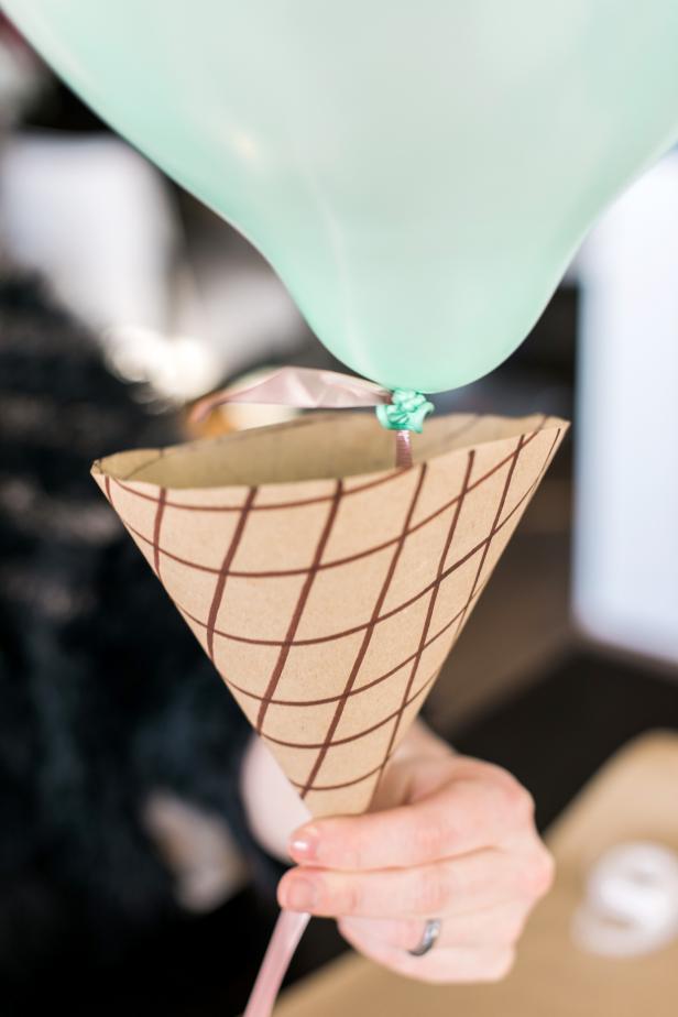 Slide the cone up the ribbon to meet the balloon. Secure the balloon to the inside of the cone with more double-sided tape.