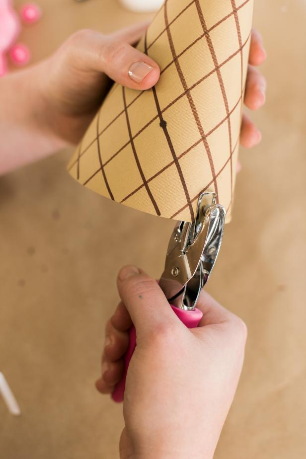 Use the hole punch to add two holes near the bottom of each side of the cone.