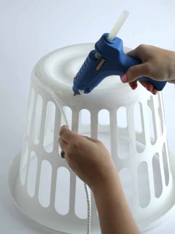 Start wrapping the white rope around the basket by placing strips of hot glue and then pushing the rope into the glue.