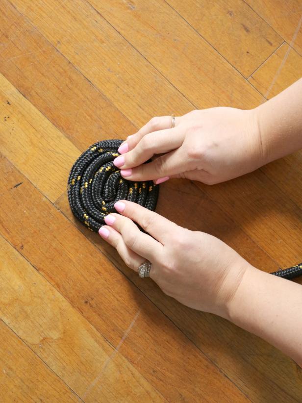 On a flat surface, start coiling the thick rope.
