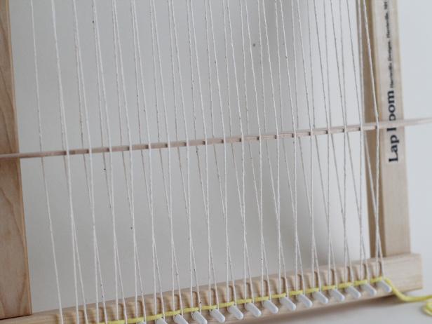 Push the first yarn down to the white pegs with your fingers.