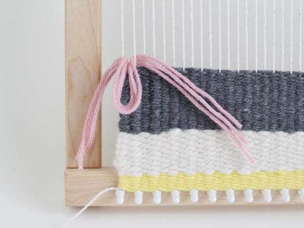 Thread the pieces of yarn behind two warp threads. Pull the middle of the pieces of yarn in between the warp threads.
