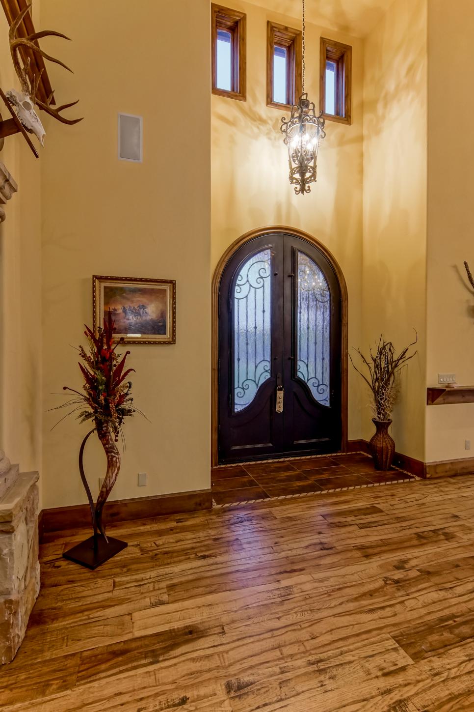 Two-Story Foyer With Plank Floors Yellow Foyer With Tall Ceiling, Arched Front Door, Hardwood Floors