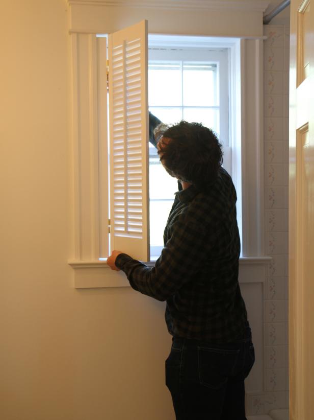 Hold the shutter in place, aligning the screws with the pre-drilled holes.