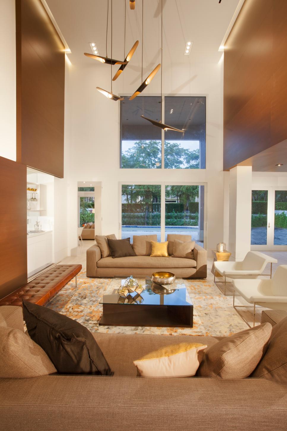 Chic, Open Living Room Features Strong Geometric Shapes & Assorted Seating Modern White Living Room With Sliding Wall & Gold Accents
