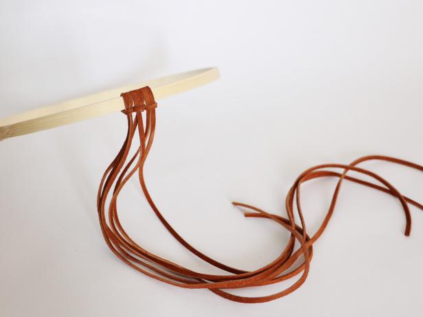 Continue to create overhand knots all the way around the hoop with all of the leather strands.