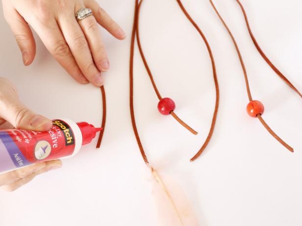 On every third strand, glue a feather. On every other strand, thread and glue on a bead. You can leave a few leather strands empty as well.