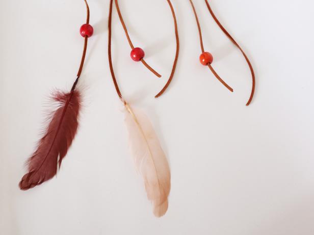 On every third strand, glue a feather. On every other strand, thread and glue on a bead. You can leave a few leather strands empty as well.