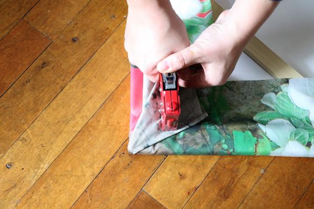 Hold the corner straight up in the air and flatten the fabric down to create a triangle. This will make a clean corner. Staple in place.