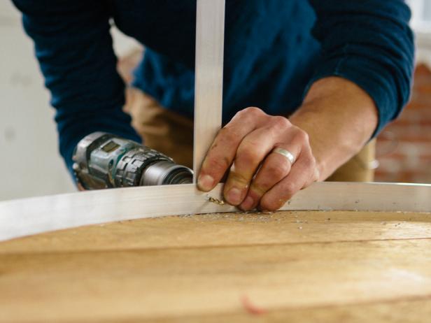 Drill a hole in an aluminum bar for wiring a pendant light.