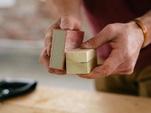 Sand wood using a sanding block to smooth out rough edges.