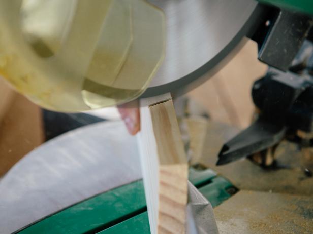 Cut wood piece at a 30-degree angle with a miter saw to make a triangular wood shelf.