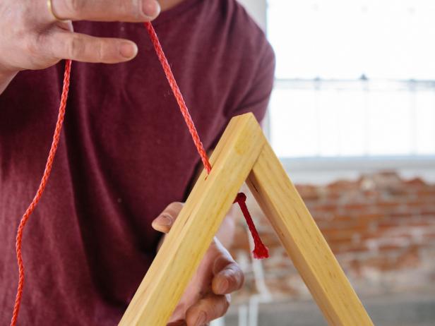 String rope through the top of the wood shelf to make a loop for hanging.