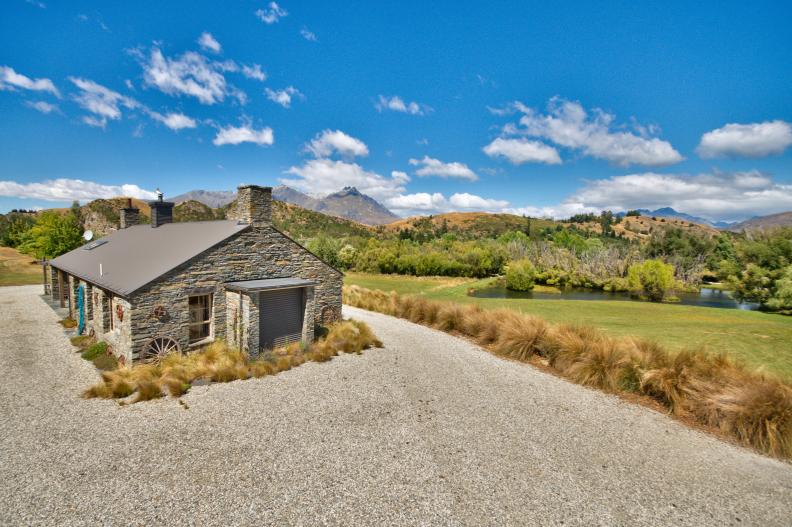 Small Farmhouse Exterior With Gravel Driveway & Rural Landscape