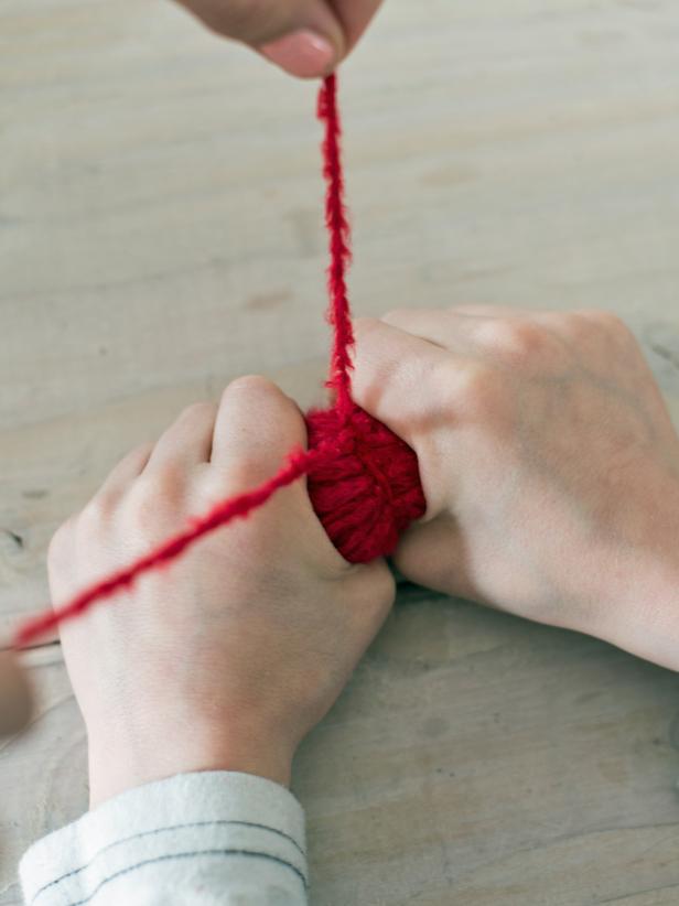 Once yarn it tied, it should be in a "bow-tie" shape. Cut loops on each and of "bow-tie" to make a pom-pom shape. Yarn can then be trimmed, so the pom-pom is a nice, round shape, or it can left shaggy.