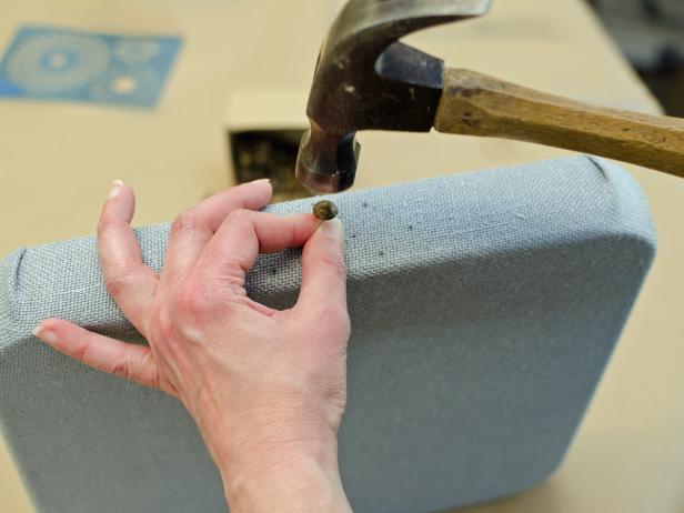 Hammer the nail heads in, on at a time, to create a graphic design.