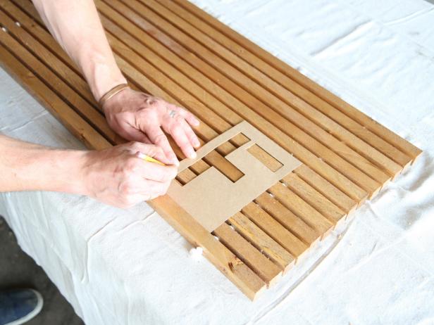 Place a lettered stencil on the wood doormat, and trace outline with a pencil.