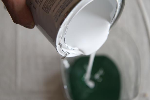 Add different amounts of white paint to three different containers of green paint to create different shades of green.
