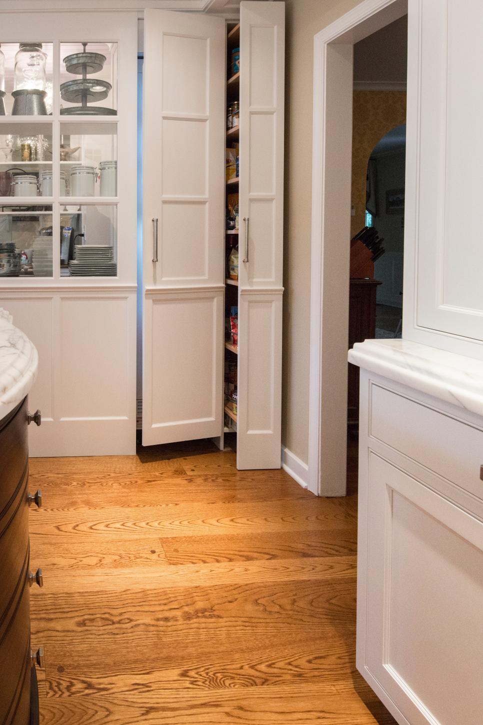 A Peek Into the Pantry Neutral Kitchen With Small Pantry, Hardwood Floor & White Cabinets
