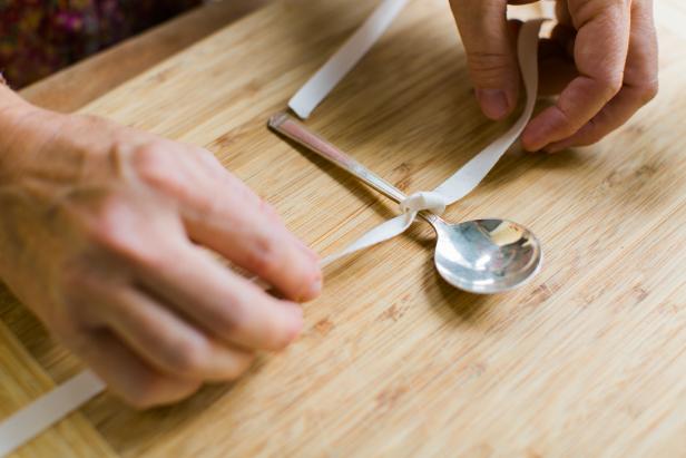 Tie a 12 inch length of ribbon around the spoon, then tie the spoon to the jar.