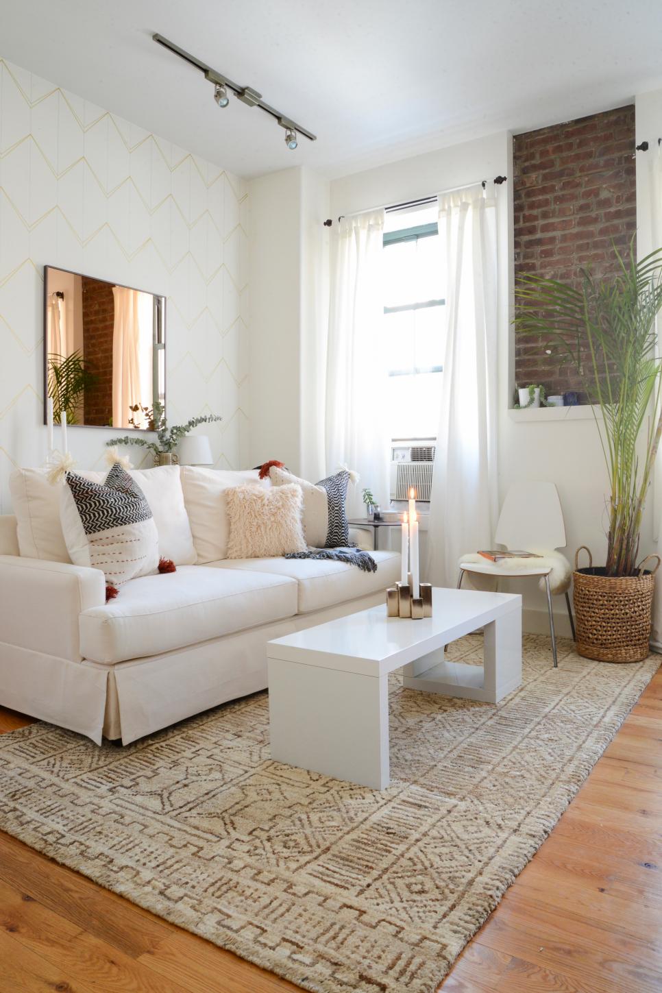 Tribal Patterned Rug Adds Movement to Small Living Space White Living Room With Cream Sofa, White Coffee Table and Tan Rug