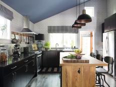 This gourmet kitchen commands attention with bold black cabinetry, crisp white subway tile, and a rustic wooden island.