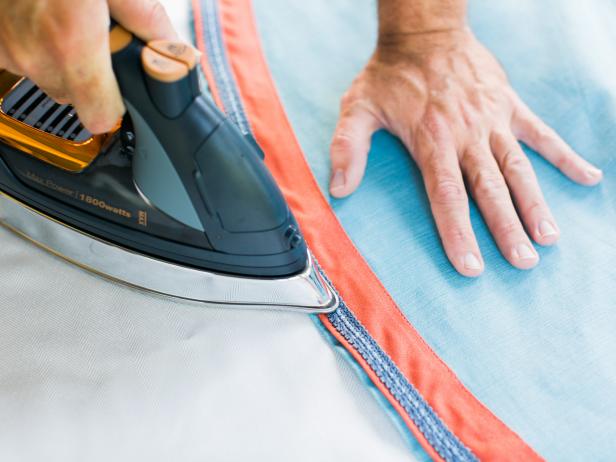 To attach the gimp to the sewed band of color, cut adhesive bonding tape to size and place it beneath the gimp, then use an iron to activate the bond. This can also be done using fabric glue by adding a bead of glue beneath the gimp, then activating the bond with the iron.