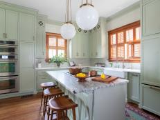 A beautiful Victorian kitchen fits perfectly with this home's overall style. Detailed wallpaper, antique-look pendant lights and pale-green cabinets are style-appropriate, while modern appliances add convenience.