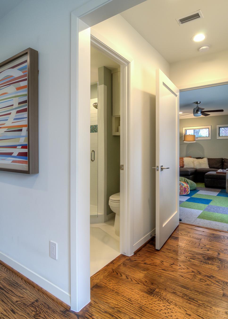 Crisp White Hall Features Warm Wood Floors White Hall Leading to Bathroom and Family Room