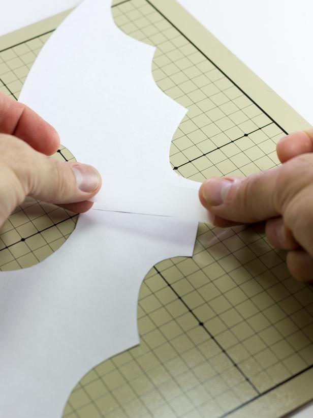 Print two copies of both the <a href="http://www.hgtv.com/content/dam/documents/HGTV/2015/cat-costume-bat-wing-right.pdf">right wing</a> and <a href="http://www.hgtv.com/content/dam/documents/HGTV/2015/cat-costume-bat-wing-left.pdf">left wing</a> templates. Lay one of each side templates together on a flat work surface to create a wing shape and tape them together at the center. Repeat for the other two templates.