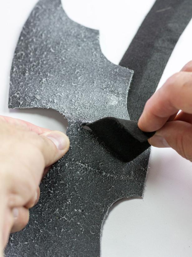 Feed the long strip through the back of one cut, over the top of the sprayed wings and through the other cut with about half of the long strip on each side of the wings. Press the strip against the adhesive.