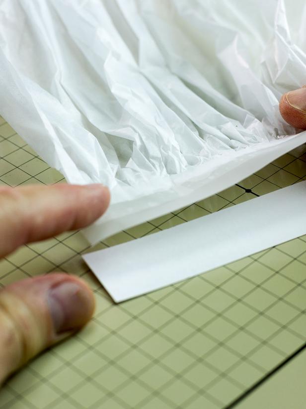 Cut an 8-1/2" by 1-1/8" piece of card stock. Use another long piece of tape to attach one side of the pleated paper to the card stock. It should be positioned so the tape securing the pleated paper is completely attached to the card stock strip.