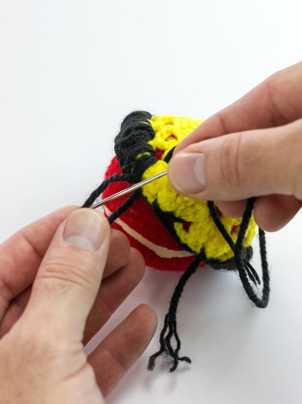 Begin covering the outside circle of the doily with black yarn. Stitch through the back of the doily and over bringing the needle through the loop you have created in a blanket-stitch style. Continue stitching in this way until you have made it all the way around the doily to add a decorative black band.