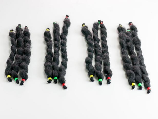Cut the chunky black yarn into 12 varying lengths between 7 and 9 inches. Thread a pony bead onto the ends of each length and tie a knot in the yarns' ends to secure the beads. Remove any excess. For the example, we made 4 lengths each with red, green and yellow beads. Group the lengths together in threes, including one of each color bead.
