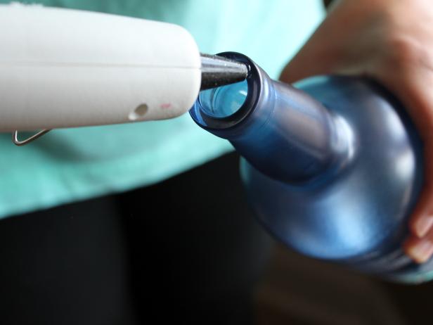 Run a thick line of hot glue around the opening of the bottle.