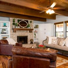 Stylish Country Living Room With Exposed Wood Beams, Large Leather Armchairs and Textured Stone Fireplace Surround
