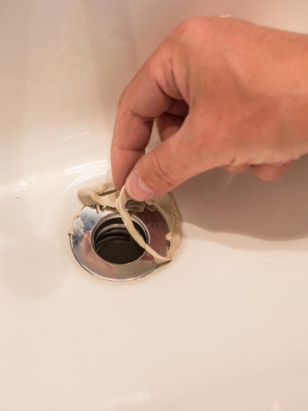 Roll a small wad of plumberâs putty between hands into a âsnakeâ thatâs long enough to reach around circumference of the drain hole. Press into place around the drain hole in sink. Push rubber seal and top of drain (flange) firmly into ring of putty. Install drain body up through sink opening and reattach the flange (inside sink) to drain opening and body (under sink). Turn flange (inside sink), until finger tight. Hold drain body in place, with pivot rod opening (for plugging drain) facing back of the sink, and tighten mounting nut (just under sink) with channel lock pliers. Tightening the drain will cause plumberâs putty to squeeze out. Pull away excess with fingers.