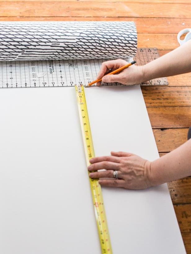 Using a measuring tape, measure wall from ceiling to top of baseboards. Transfer this measurement to first panel of paper, adding about an inch allowance at the top. Draw a straight cut-line with a pencil and a clear quilting ruler or square (to ensure a straight line.) Cut along line with sharp scissors. Determine start point of first wallpaper panel on the wall. Mark with a pencil. Then, draw a straight vertical (or plumb line) using a pencil and level. Since most walls and ceilings arenât level or square, use this plumb line as a guide when hanging the first piece of paper. Tip: When working with a repeating pattern, this starting plumb line can be in the center of the main wall, a corner, up against cabinetry, etc. If hanging a mural, like this one, start from left to right (or however mural comes off the roll.)