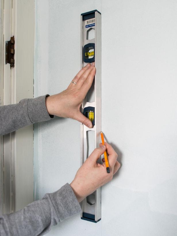 Using a measuring tape, measure wall from ceiling to top of baseboards. Transfer this measurement to first panel of paper, adding about an inch allowance at the top. Draw a straight cut-line with a pencil and a clear quilting ruler or square (to ensure a straight line.) Cut along line with sharp scissors. Determine start point of first wallpaper panel on the wall. Mark with a pencil. Then, draw a straight vertical (or plumb line) using a pencil and level. Since most walls and ceilings arenât level or square, use this plumb line as a guide when hanging the first piece of paper. Tip: When working with a repeating pattern, this starting plumb line can be in the center of the main wall, a corner, up against cabinetry, etc. If hanging a mural, like this one, start from left to right (or however mural comes off the roll.)