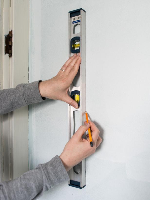 Using a measuring tape, measure wall from ceiling to top of baseboards.  Transfer this measurement to first panel of paper, adding about an inch allowance at the top.  Draw a straight cut-line with a pencil and a clear quilting ruler or square (to ensure a straight line.)  Cut along line with sharp scissors.  Determine start point of first wallpaper panel on the wall.  Mark with a pencil.  Then, draw a straight vertical (or plumb line) using a pencil and level.  Since most walls and ceilings arenât level or square, use this plumb line as a guide when hanging the first piece of paper.  Tip: When working with a repeating pattern, this starting plumb line can be in the center of the main wall, a corner, up against cabinetry, etc.  If hanging a mural, like this one, start from left to right (or however mural comes off the roll.)