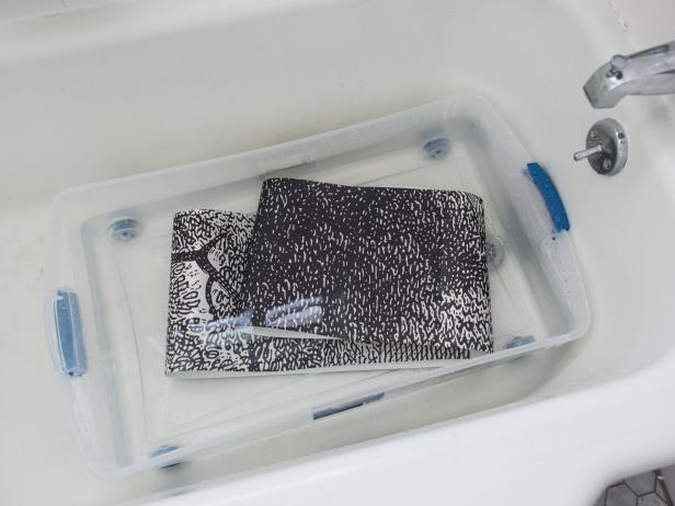 Fill plastic tub or bathtub with enough clean water to submerge wallpaper completely. Grab top and bottom sides of wall paper panel and fold each end length-wise to meet in the middle with glued sides together. Then fold each end into center again to âbookâ the paper. Push into water until paper is covered. Follow manufacturerâs instructions for duration paper should be submerged in water. Once instructed time has passed, remove paper from water and allow excess to drip off into tub. Unfold paper and press onto wall, lining up one edge with the penciled plumb line. Most wallpaper paste allows for shifting once applied to wall, in order to ensure proper placement and removal of bubbles and wrinkles. Tip: If working in a room with high walls, this is definitely a job that is easier with two people!